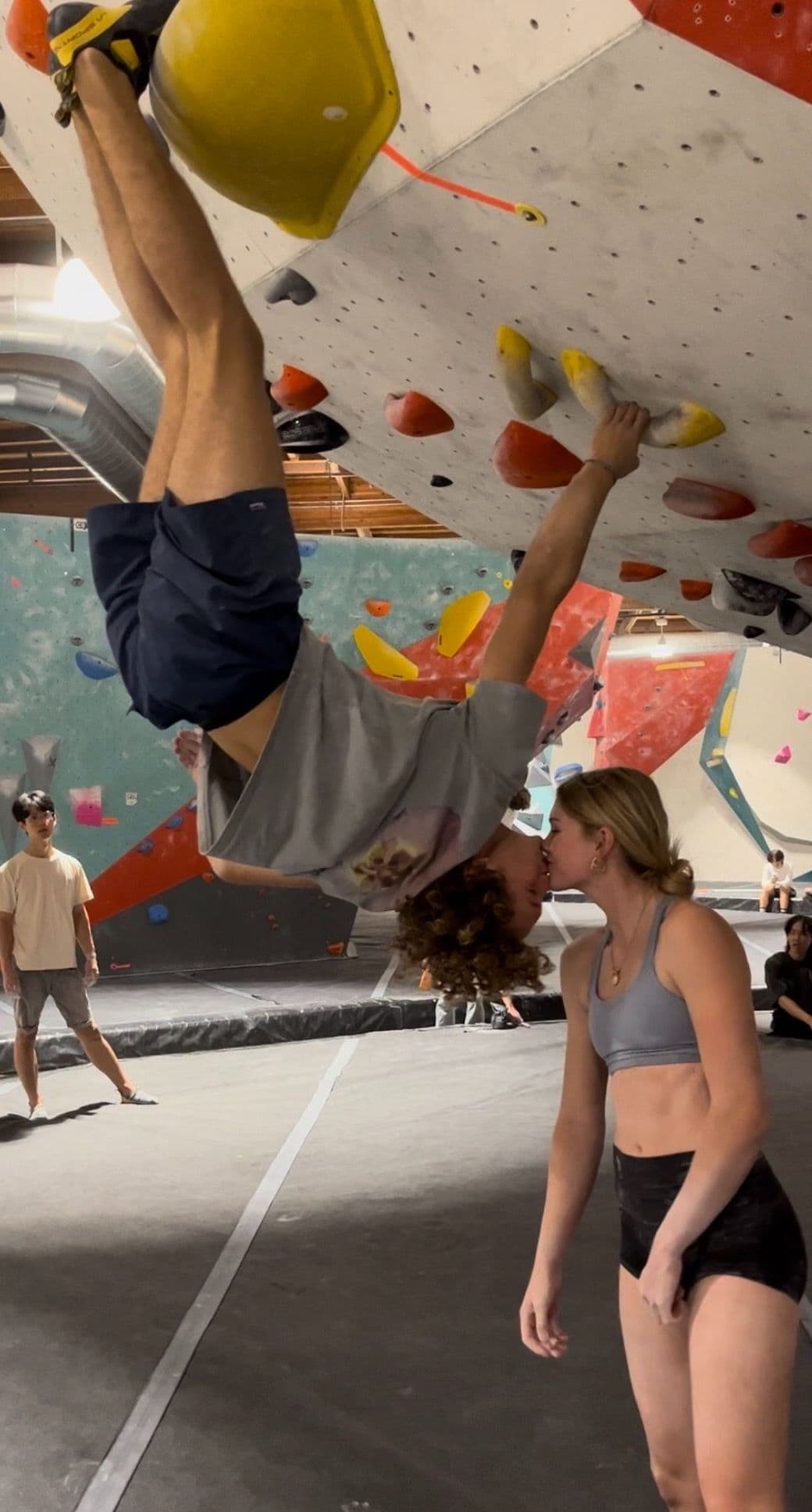 two climbers kissing at a bouldering gym